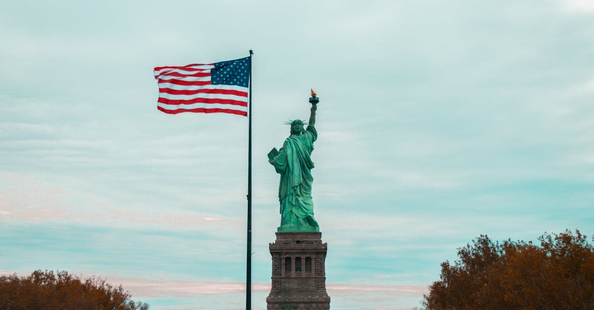 Statue of Liberty standing beside the American flag, a landmark destination covered by travel insurance for America.