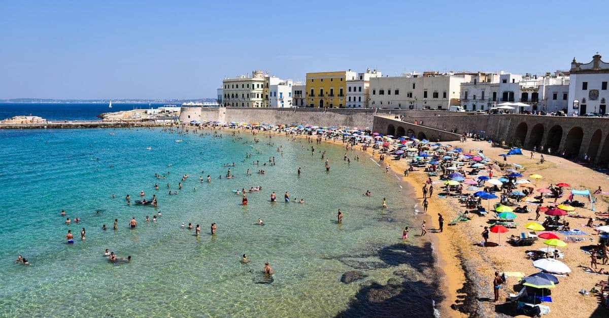 Spiaggia di Gallipoli con ombrelloni colorati e bagnanti, una delle mete più amate per le vacanze pasqua 2026.