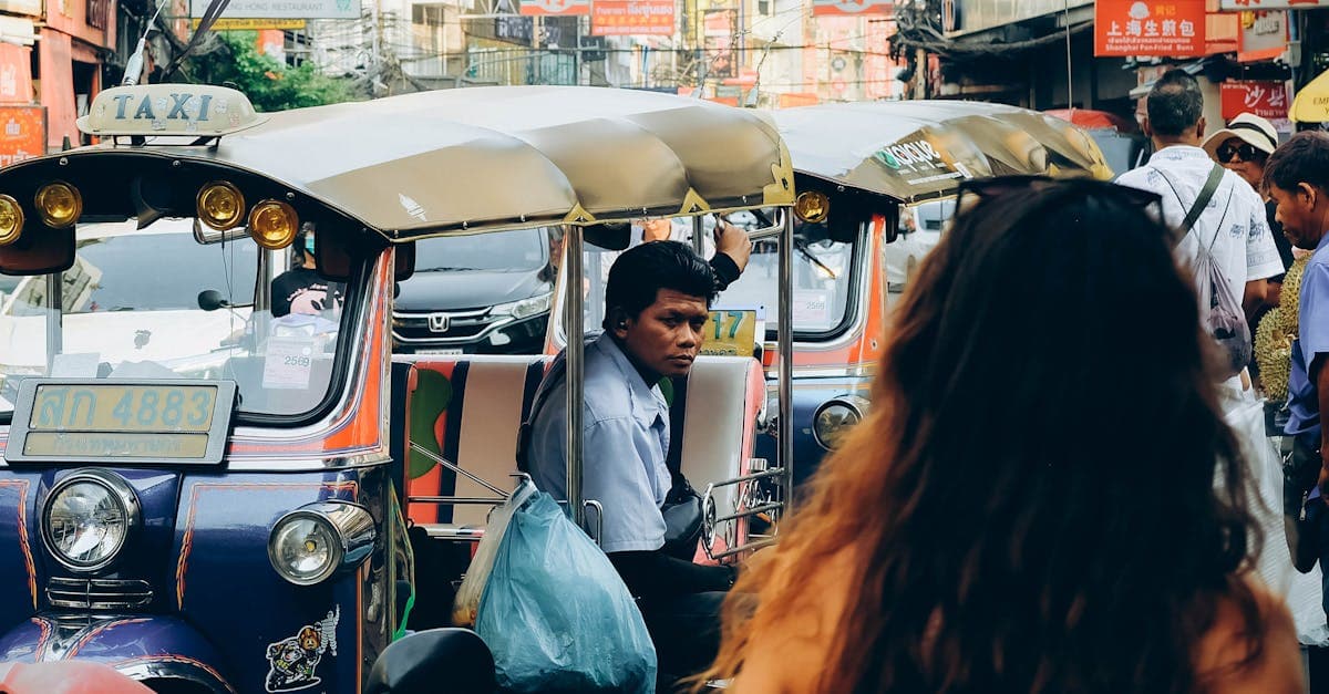 Tętniąca życiem ulica Bangkoku z tuk-tukiem i tłumem turystów — gdzie uważać na oszustów.