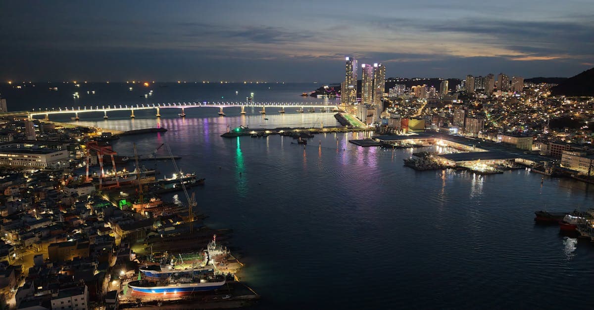 부산의 주요 명소인 광안대교의 야경을 공중에서 찍은 도시불 조명과 수면 반사