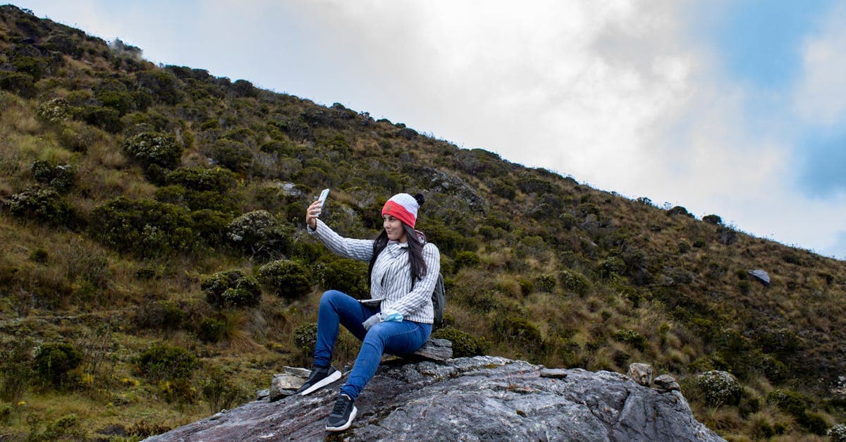 Mujer en lo alto de un cerro tomando una selfie rodeada del paisaje verde colombiano, conectada sin roaming