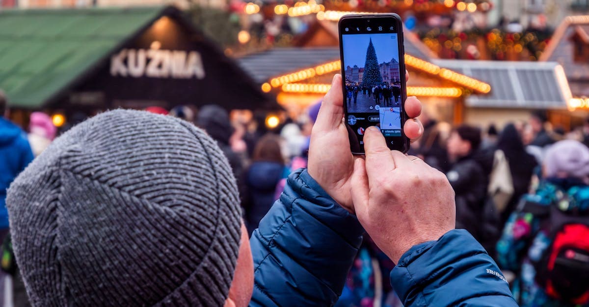 Mężczyzna fotografuje świąteczny jarmark telefonem sprawdzając pakiety roamingu T-Mobile podczas zimowych podróży