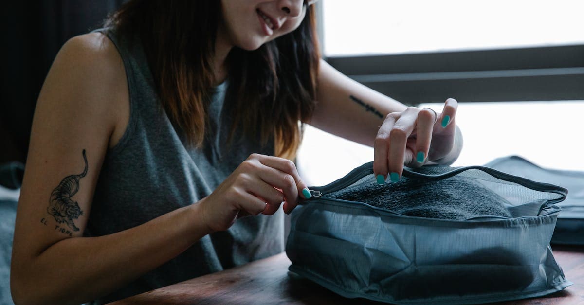 Kvinna ler när hon zippar sin travel bag inomhus, förbereder sig inför en budgetresa.