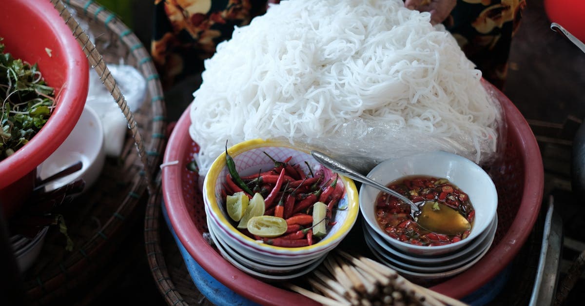 Bowl of Vietnamese noodles with fresh herbs, chili, and fish sauce at a traditional Hue market stall