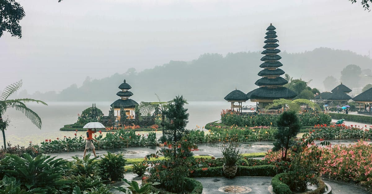 Serene Balinese temple surrounded by lush green gardens and tranquil lake during the rainy season