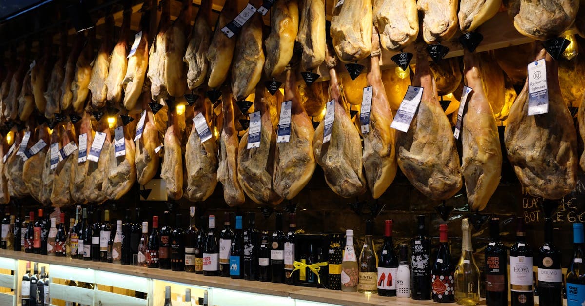 Rows of hanging jamón ibérico with wine bottles in a traditional Barcelona market, Spain's most iconic food