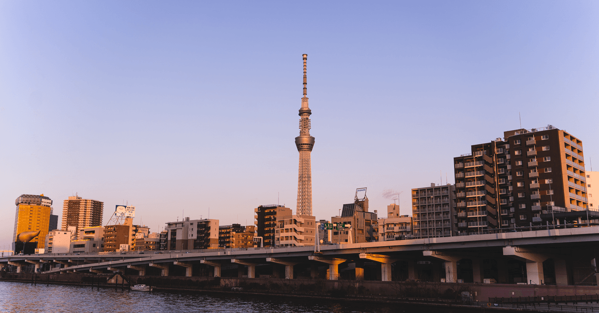隅田川沿いに夕暮れ時に輝く東京スカイツリーと都市の夜景。韓国へ入国する日本人旅行者の出発地。