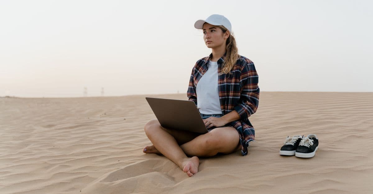 Kobieta pracująca na laptopie na pustyni, symbolizująca zarobki i wolność finansową programu work and travel.