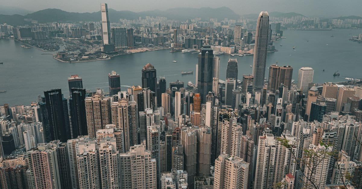 Aerial panorama of Hong Kong's central business districts and Victoria Harbour highlighting dense urban skyscraper clusters.