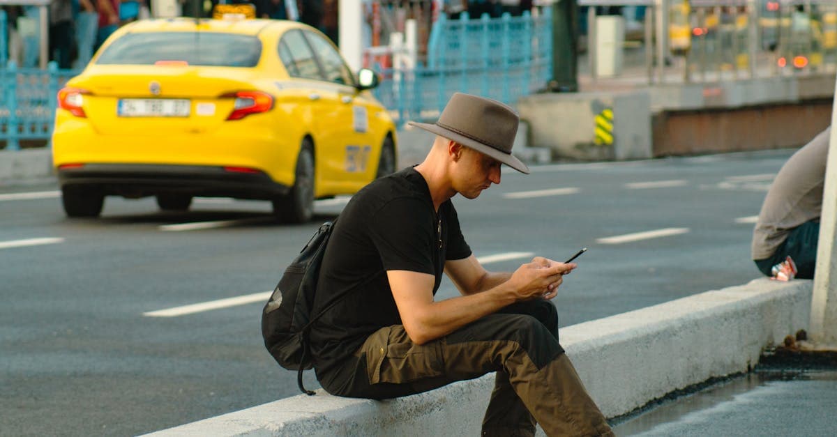 Mężczyzna w kapeluszu siedzi na krawężniku i sprawdza koszty t mobile roaming za granicą