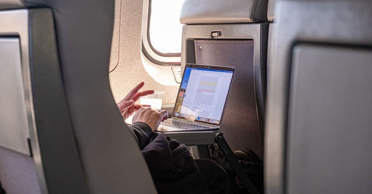 Passenger using a laptop on board, making the most of time during flight connections between destinations.