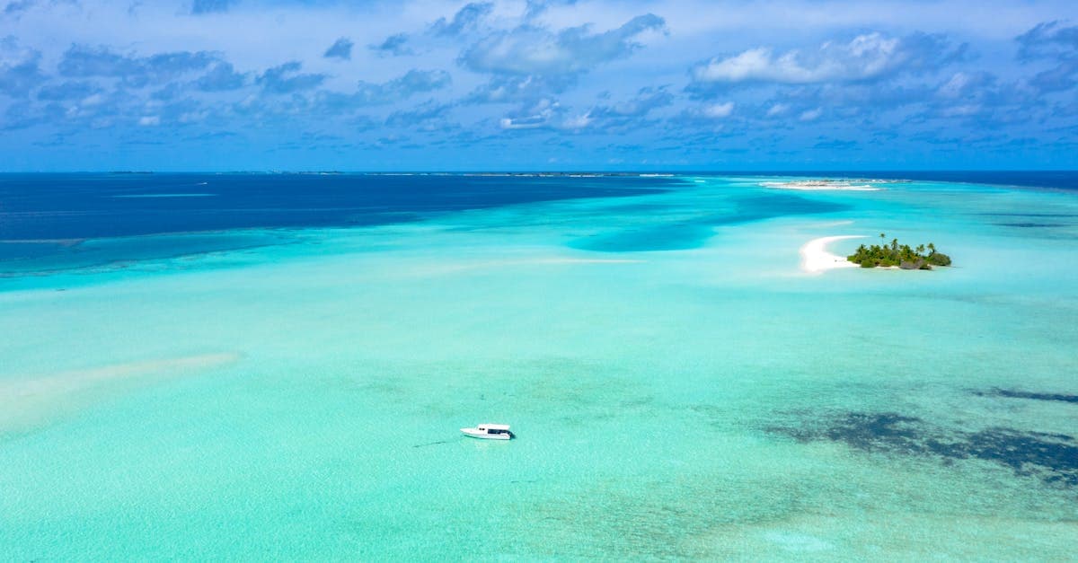 Türkisblaues Meer und abgelegene Insel aus der Luft – beste Reisezeit Malediven für Tauchen und Schnorcheln