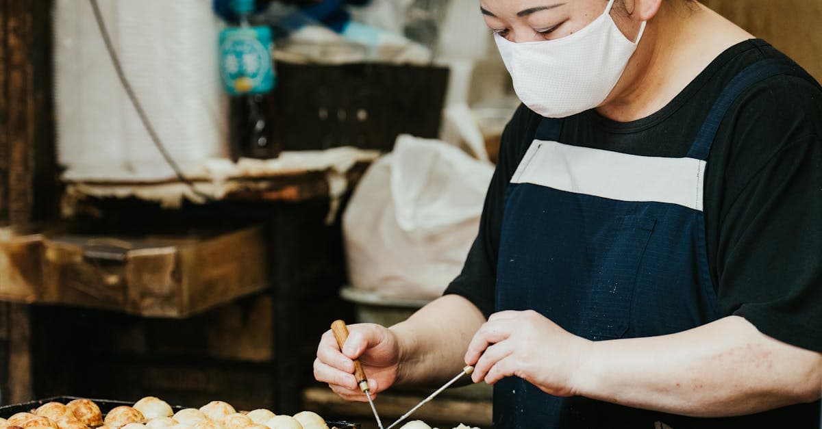 屋外市場でたこ焼きを手際よく焼く屋台の職人、日本のソウル フードを象徴する活気ある光景