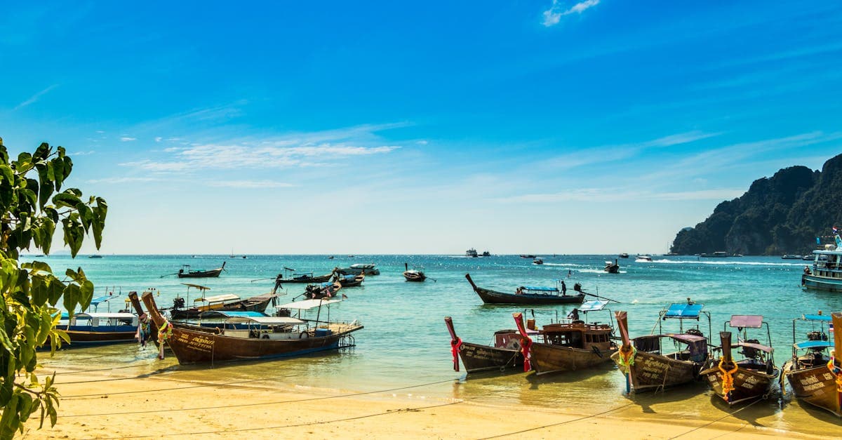 Bateaux traditionnels thaïlandais ancrés sur une plage ensoleillée illustrant la meilleure période de météo thaïlande