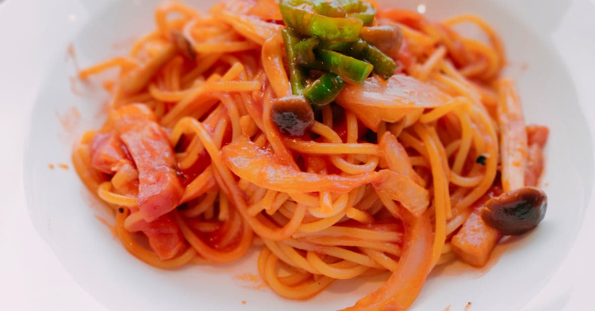 Mouthwatering spaghetti topped with mushrooms, bell peppers, and tomato sauce, served on a ceramic plate.