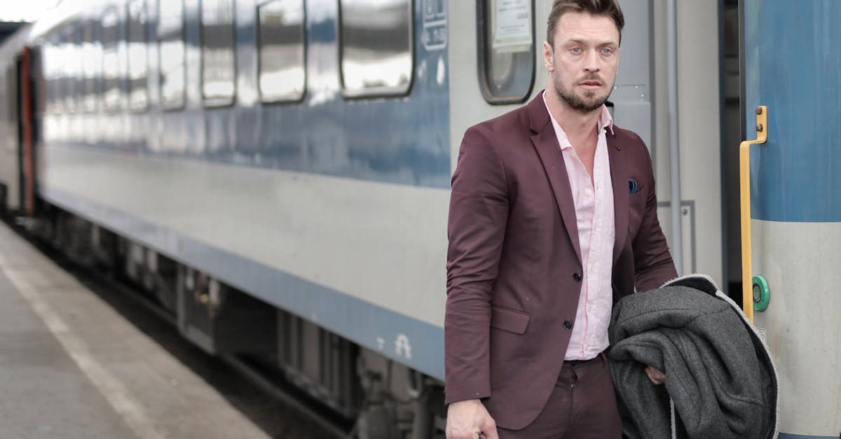 Man i kostym kliver av ett tåg med en travel bag och kavaj i handen.