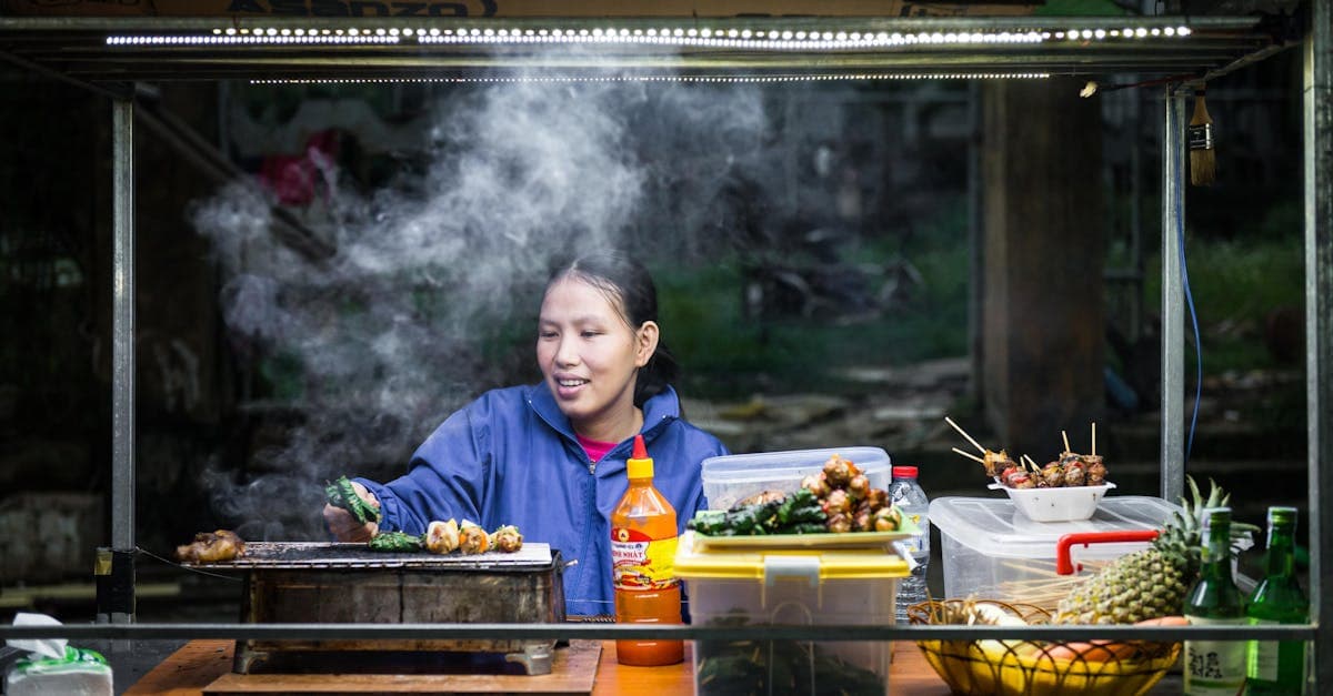 Vendeur grillant des brochettes dans la vapeur d'un marché animé de Hoi An au Vietnam