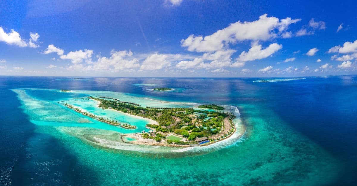 Stunning aerial view of a tropical island surrounded by turquoise waters in the Maldives.