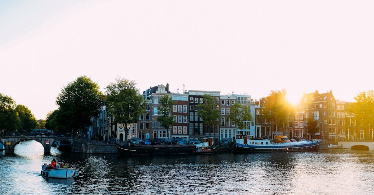 Historic Amsterdam canal at sunset with moored boats, a scenic sight before day trips from the city