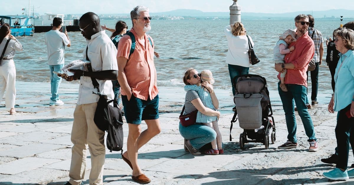 Adults and children relaxing by a sunny waterfront, highlighting what to pack alongside a travel stroller
