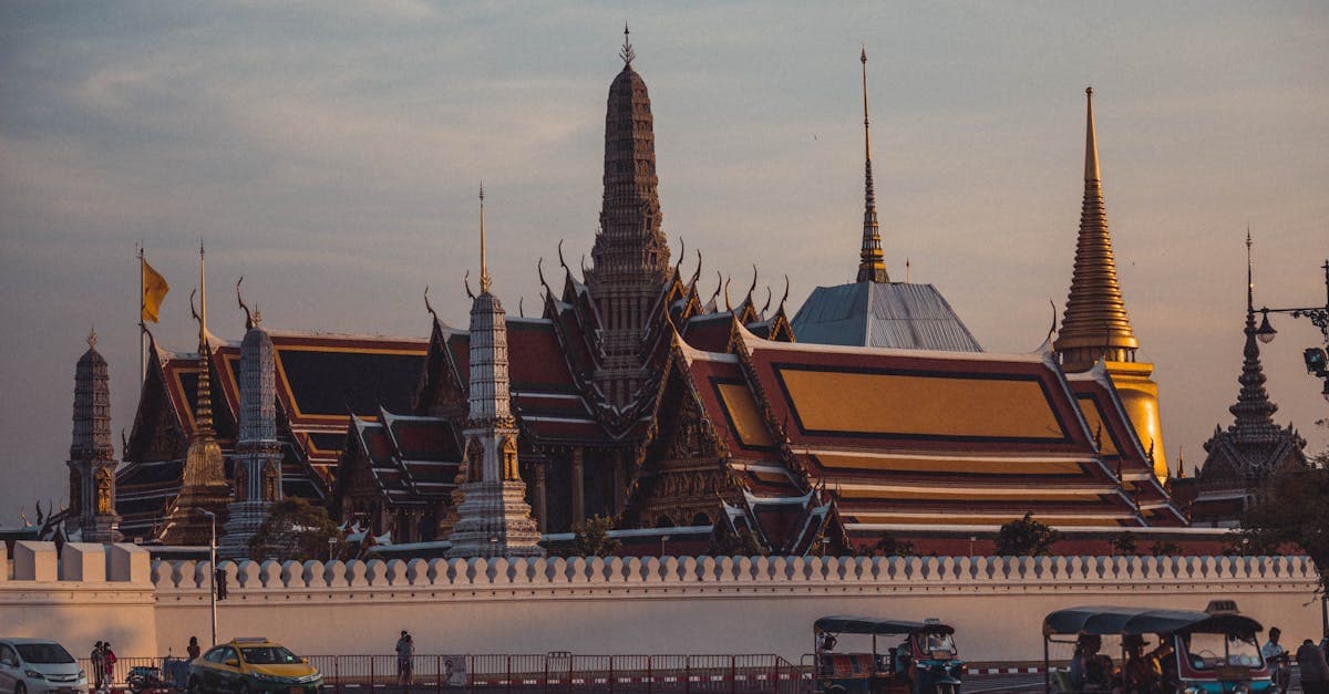 Wat Phra Kaew's intricate gilded architecture glowing at dusk in Bangkok's Grand Palace complex.