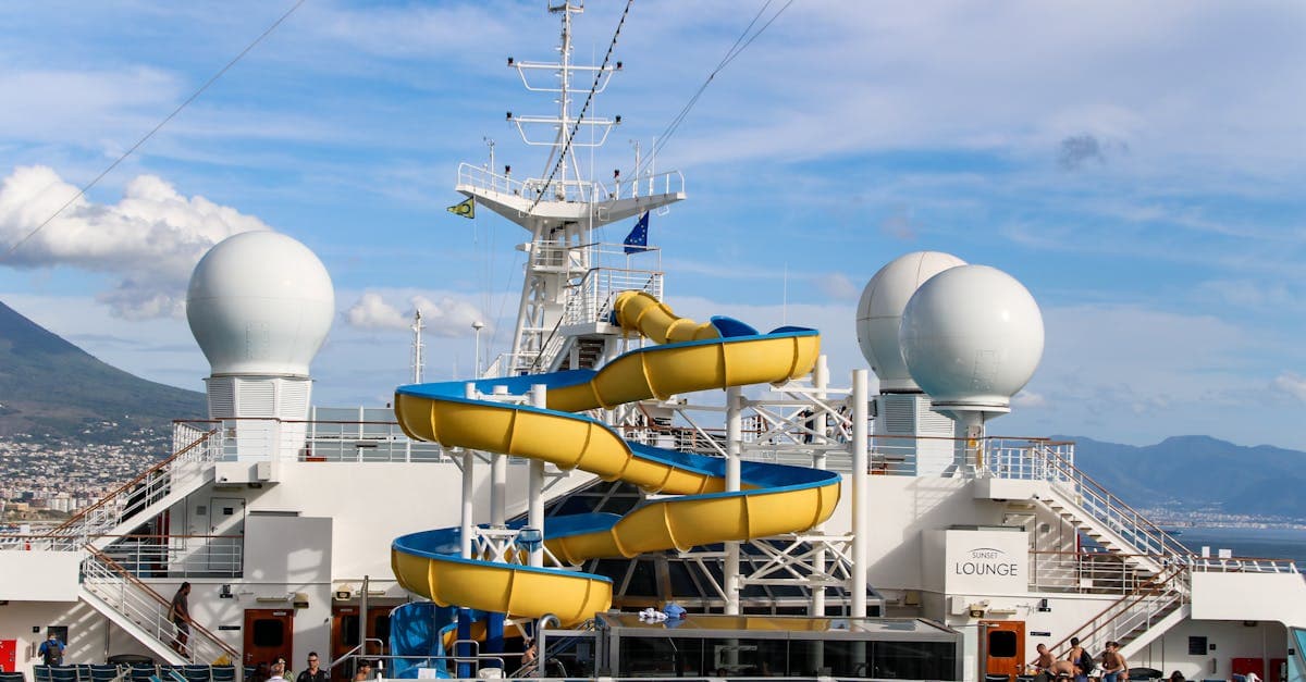 Vibrant yellow waterslide towering above the cruise deck, a standout feature when comparing Carnival Adventure and Splendor