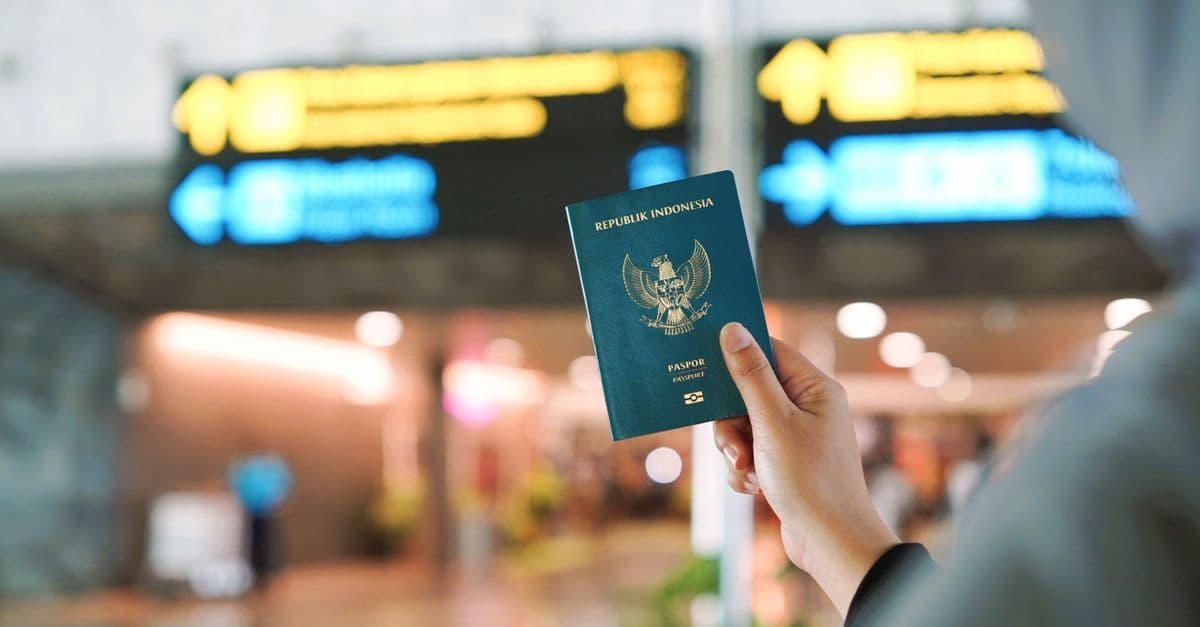 旅客於機場候檢區舉起護照,背景可見指示牌,象徵辦理入境與海關程序。