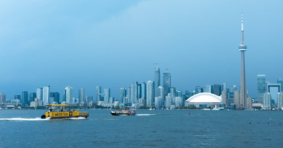 Toronto's CN Tower and Lake Ontario water taxi on a clear day, gateway for toronto to tokyo flight deals![image