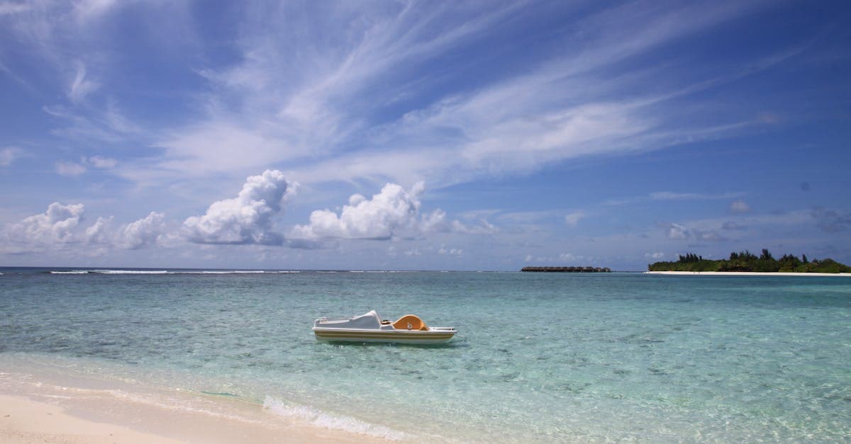 Kleines Boot an einem maledivischen Strand mit klarem Wasser und hellem Himmel zur Regenzeit