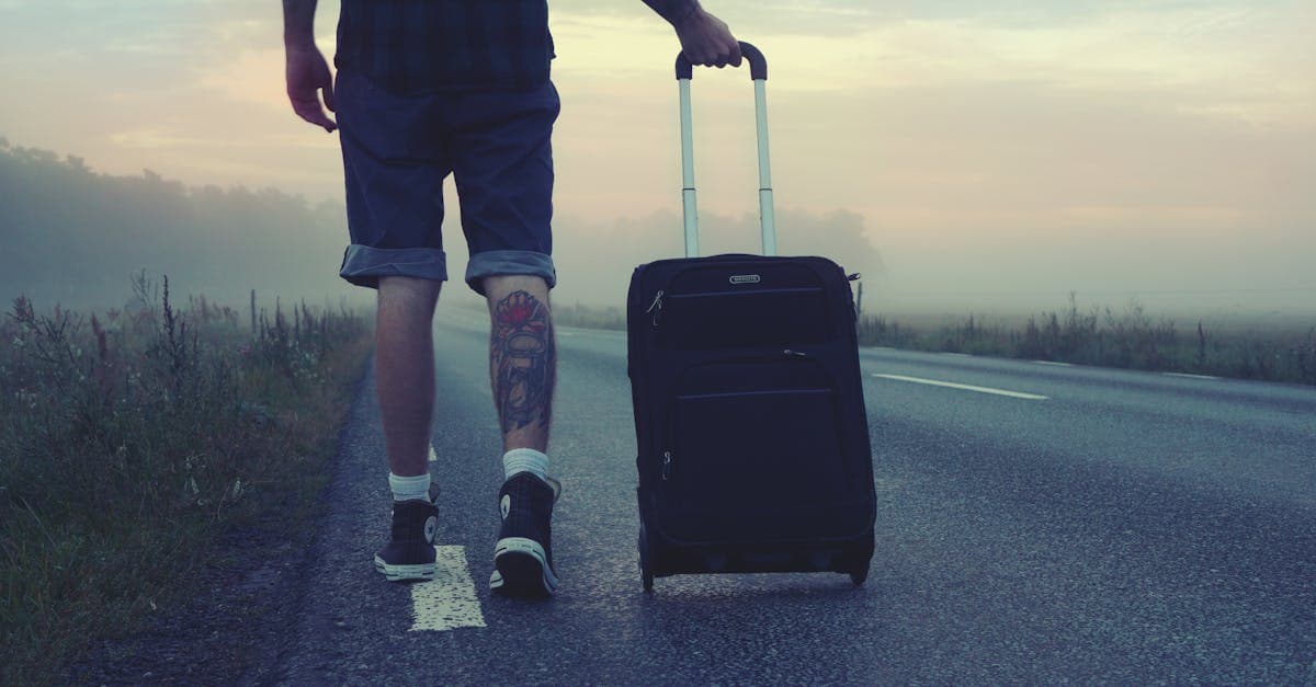 Man går med resväska längs en dimmig väg vid soluppgång, symboliserar val av travel bag för resan.
