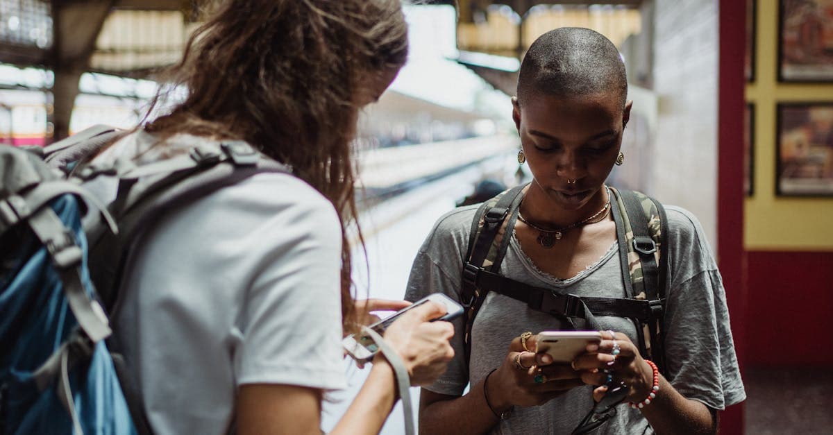 Zwei Reisende mit Smartphones am Bahnhof bleiben dank mobilem Internet günstig verbunden