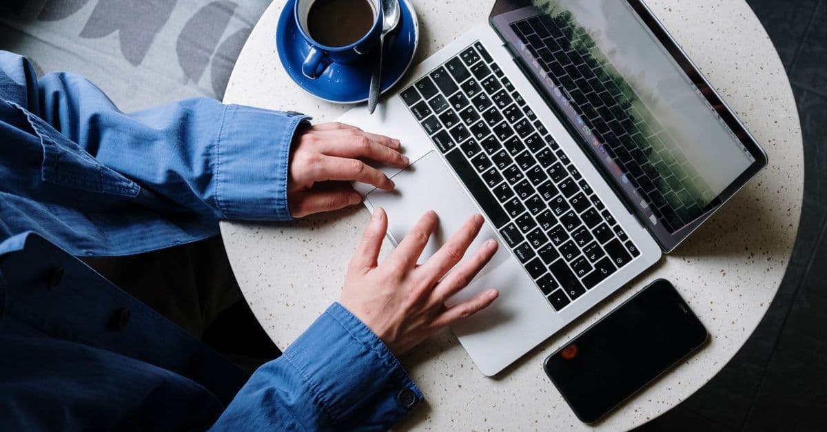 Person arbejder på laptop ved en kop kaffe og holder sig online under rejse i Spanien