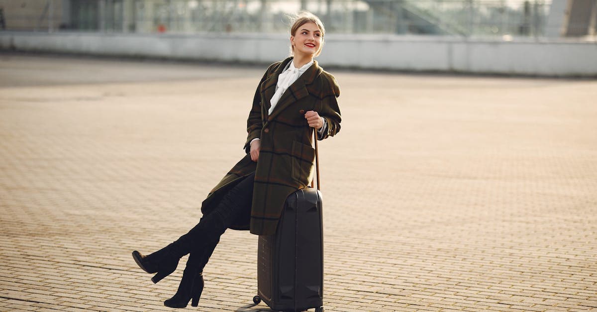 Femme souriante en manteau à carreaux assise sur ses bagages dans un terminal d'aéroport