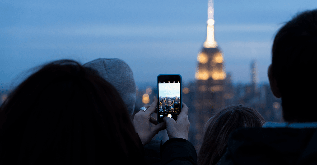 Tourists photographing the Empire State Building at dusk while staying connected through international travel eSIM options.