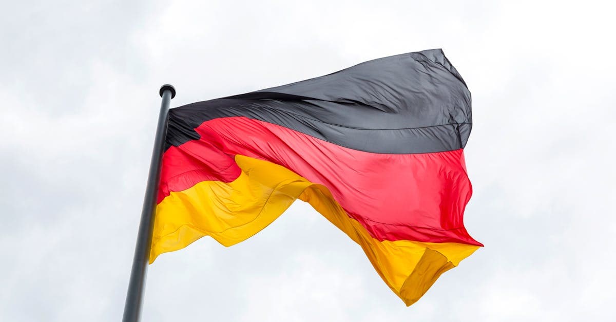 Vibrant German flag flying against a backdrop of a cloudy sky, symbolizing national pride.