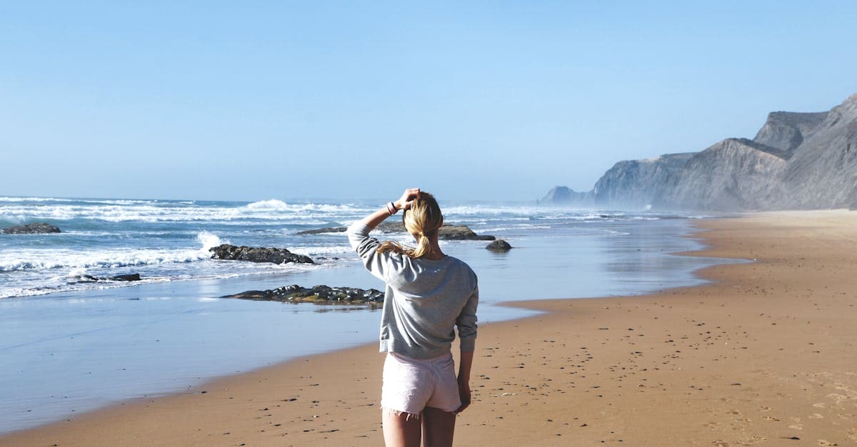 Vrouw staat peinzend aan de kust en geniet van de rust van alleen op vakantie gaan.
