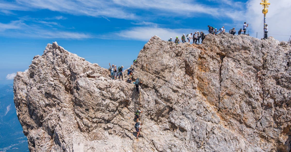 Abenteurer besteigen den berühmten Zugspitze-Gipfel unter klarem Himmel – eines der schönsten Bucket-List-Erlebnisse in Österreich.