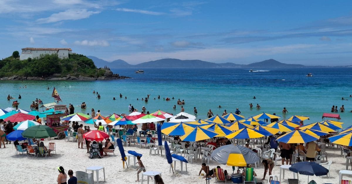 Praia animada com guarda-sóis coloridos e banhistas aproveitando o verão na Europa sob sol forte