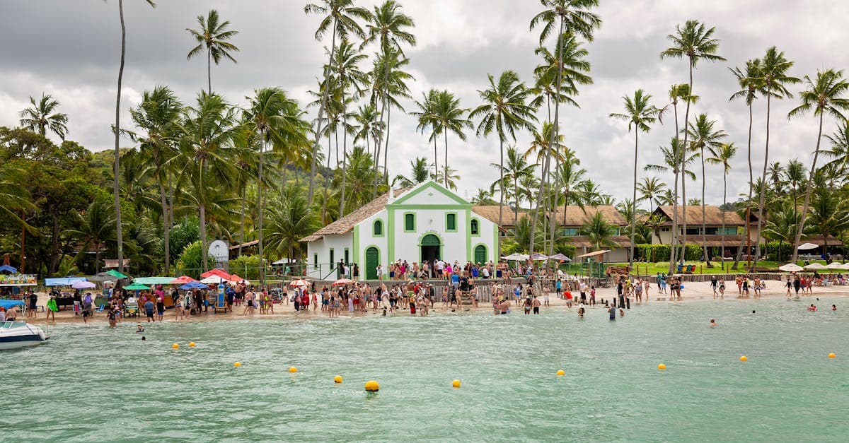 Praia movimentada com a Igreja de São Benedito ao fundo, palmeiras e turistas nos países baratos para viajar em 2026