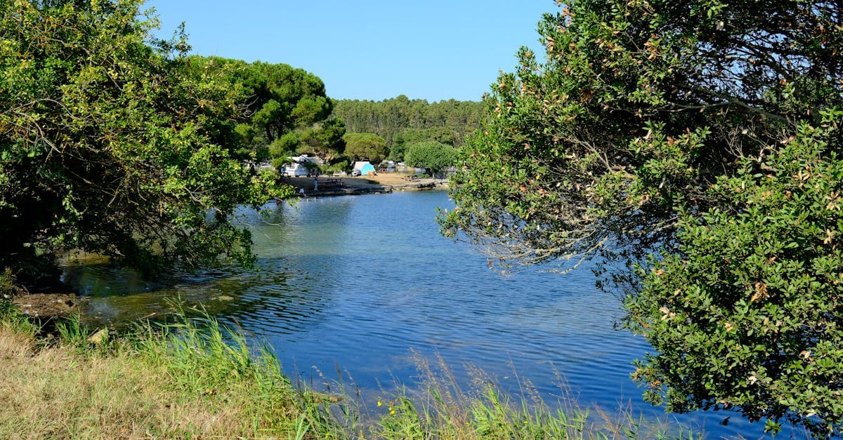 Rustig meer met kampeerders in weelderige natuur, een beeld dat veelgemaakte misvattingen over camping Zuid-Frankrijk weerlegt
