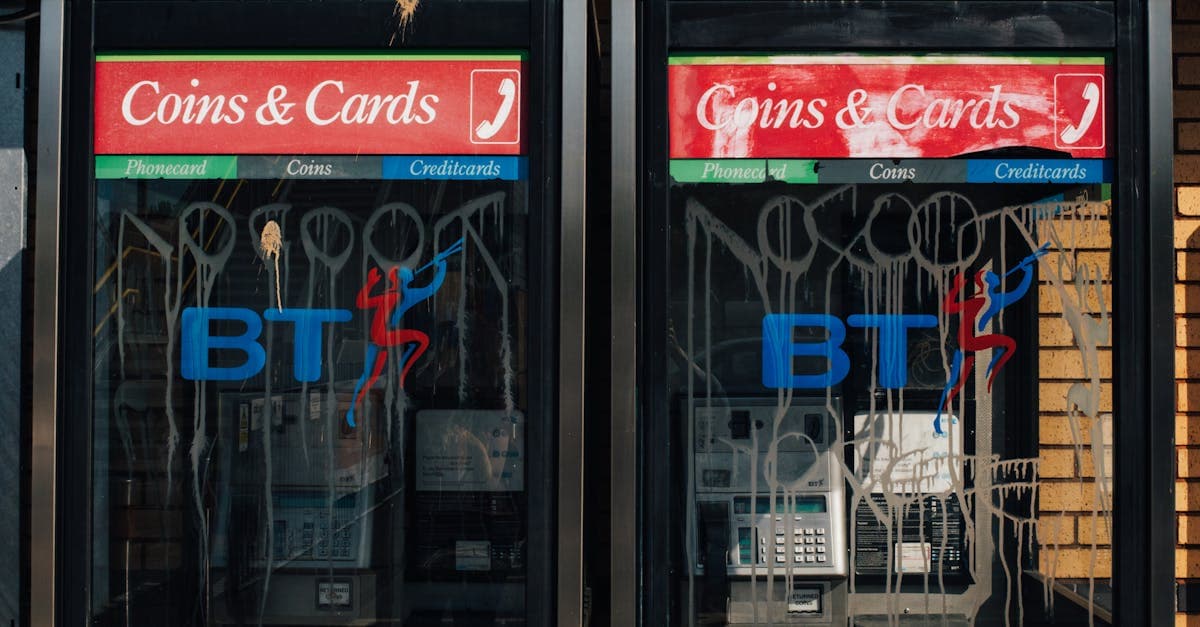 Weathered British phone boxes displaying BT logos on a city street, highlighting UK phone infrastructure.