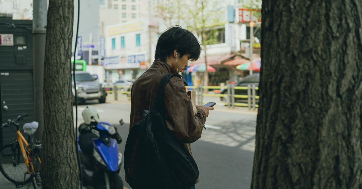 서울 번화가를 걷는 젊은 남성이 스마트폰으로 모바일 데이터를 활용해 기타 국내 드라마 갤에 접속하는 장면