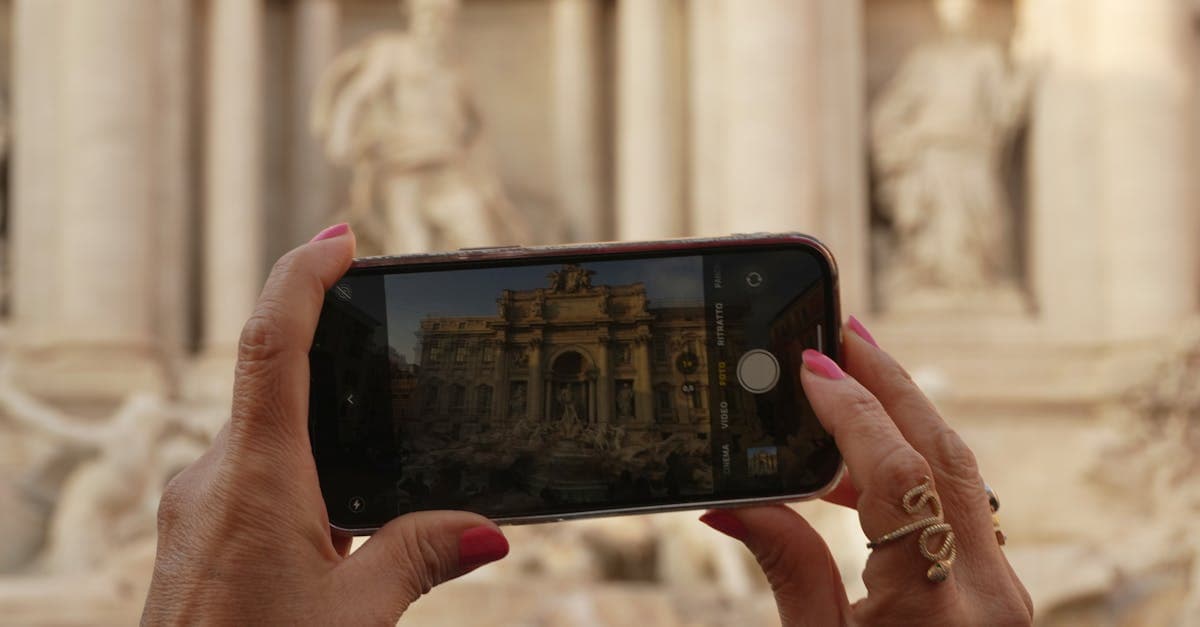 Mani fotografano la Fontana di Trevi con uno smartphone, connessione essenziale per i tifosi MotoGP in viaggio.
