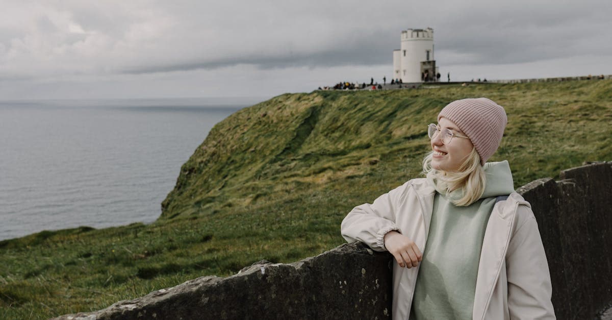 Woman smiling at the Cliffs of Moher in June, capturing the nicest month to visit Ireland