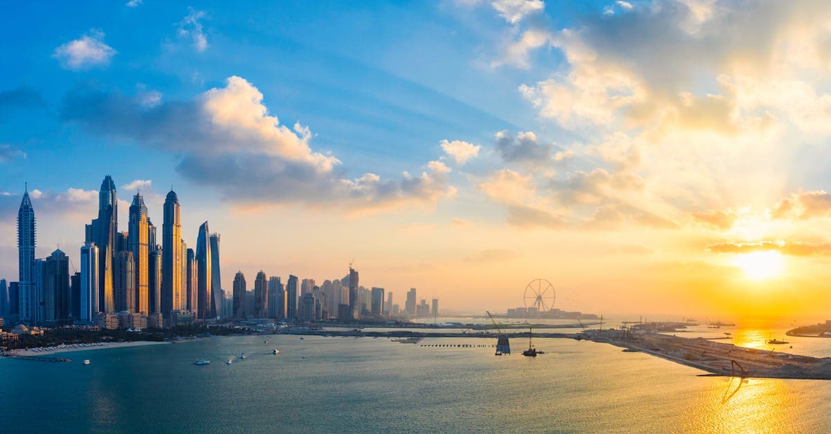 Skyline di Dubai al tramonto con grattacieli illuminati riflessi sull'acqua, per conoscere il meteo Dubai mensile
