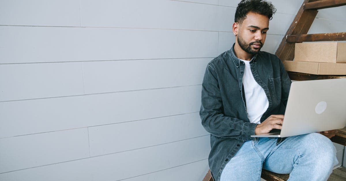 Young remote worker using a laptop on indoor stairs, preparing to apply for a digital travel eSIM visa