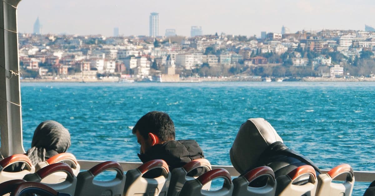Fahrgäste auf einer Fähre über den Bosporus blicken auf die Häuser von Istanbul.