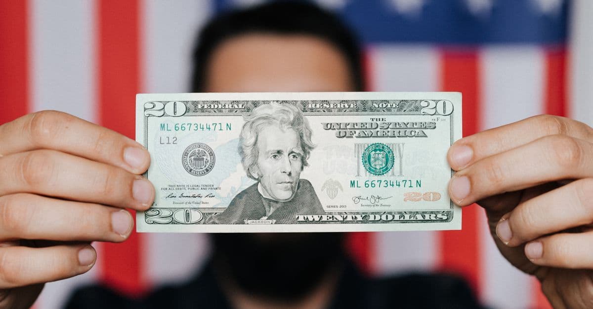 Man holding a US dollar bill against an American flag highlighting high mobile roaming costs