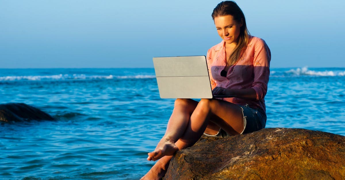 Kvinde arbejder på laptop ved havet i Sri Lanka og nyder bærbar wifi på rejsen
