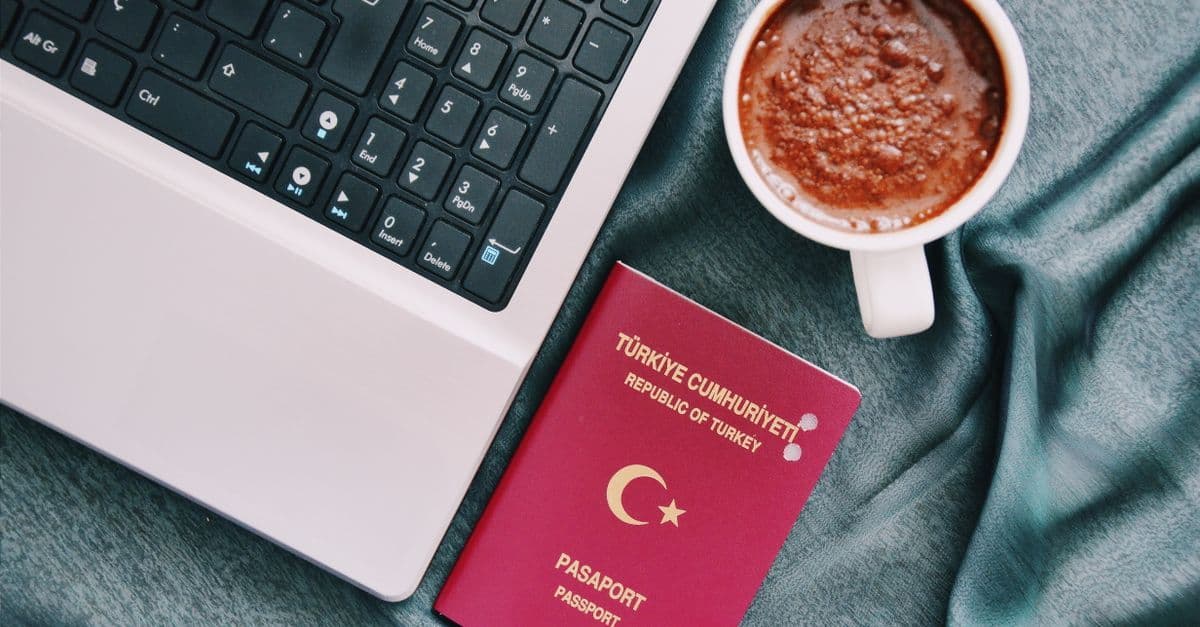 Türk pasaportu ve dizüstü bilgisayar, yunanistan vize başvurusu için gerekli belgeleri sembolize ediyor.